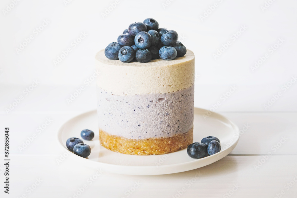 Wall mural vegan vanilla blueberry cheesecake against white background.