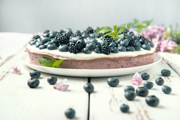 Cottage cheese casserole with blackberry and blueberry on white Provence style table.
