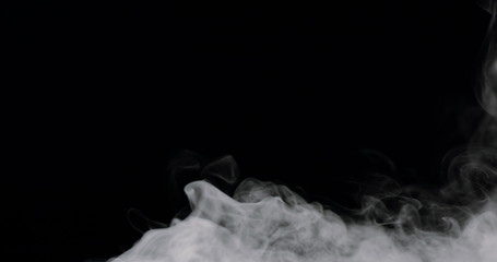 wispy smoke rolling along the bottom of the frame, against a black background.