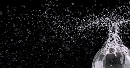 water bubble bursting against a black background.