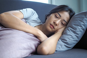 A depressed Asian woman cuddles a pillow and feels sorry after an altercation with a close friend...