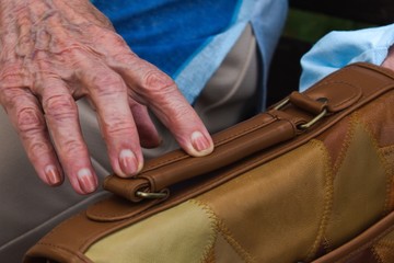 elderly woman hand touches the handbag