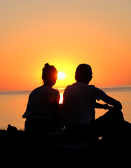 two young people sitting on the background of the sunset. Europe. 14.08.2020