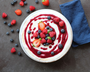 Top view of whole cheesecake with berries and coulis on top