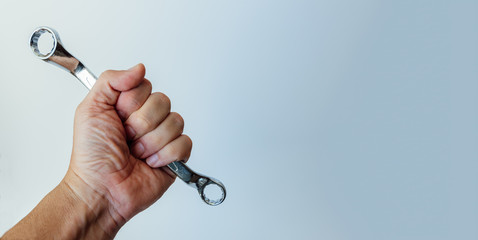 Clenched fist of man holding steel tool isolated on soft background