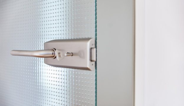 Offene Glastür im Büro mit Türklinke und Schlüssel im Türschloss