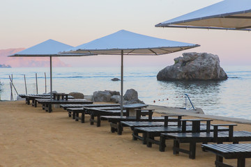 beach by the sea with sun loungers and parasols in the morning at sunrise