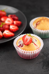 Strawberry cupcake with fresh strawberries on black concrete background