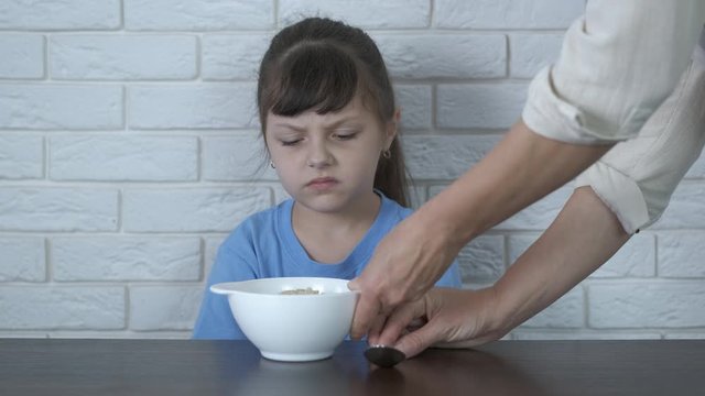 Mother's porridge. The mother gives her daughter oatmeal, the child refuses porridge.