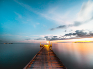 Fototapeta na wymiar Wooden jetty at sunset over the ocean, long exposure