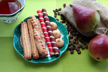 Cookies on a green saucer. Pears on sacking.