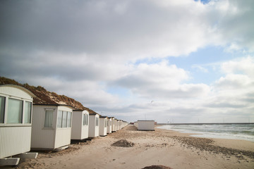 A row of beach cabins with clouds