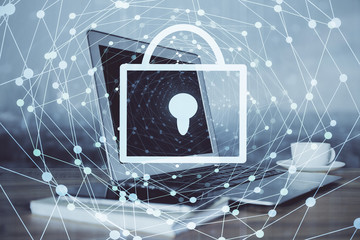 Double exposure of desktop with computer and lock icon hologram. Concept of data safety.