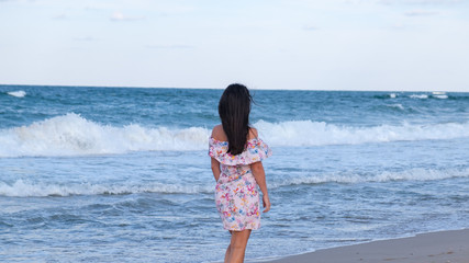 young woman walking on the beach, back view