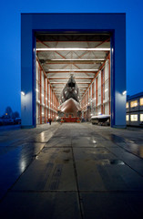 Transport of a super sailing yacht at the shipyard. Boat casco. Shipbuiling industry. At night. Shed.