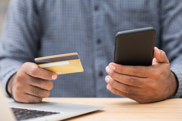 Close up businessman hand holding credit card and using smartphone and laptop computer to Financial administration. Shopping online, Internet banking concept.