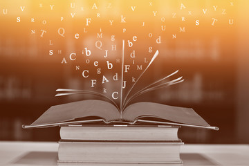 Open book on the table and English alphabet Floating above the book in the library and blur...
