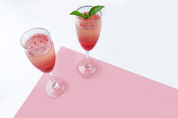 Cooling Rossini italian alcoholic cocktail with sparkling wine, strawberry puree, ice cubes in champagne glass on white background. Refreshing summer lemonade or ice tea served with mint leaves