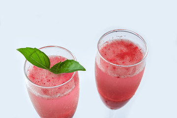 Cooling Rossini italian alcoholic cocktail with sparkling wine, strawberry puree, ice cubes in champagne glass. Refreshing summer lemonade or ice tea served with mint leaves