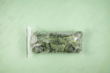 Frozen vegetables. Fresh leaves of kale cabbage in a freezer bag on a green background. Copy space, horizontal orientation