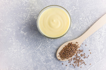 Glass of yellow mango or banana yogurt or smoothie  with flax seeds on gray background. Healthy...