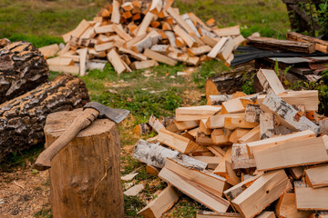 A pile of birch firewood on the green grass. Split logs. Sawdust. Selective focus.