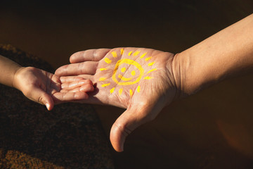 mens hand with paint yellow sun with smile stretches out his hand to child's palm