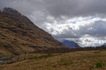 Fototapeta na wymiar The Mountain Scenery of Glen Etive, with remnants of snow clinging to the peaks looking down over the Valley Floor in April.