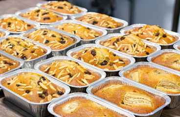 Image select focus of banana cake in square containers sprinkled with almonds and raisins or bread, flat lay view. several pieces on a wire rack is desserts and sweet food.