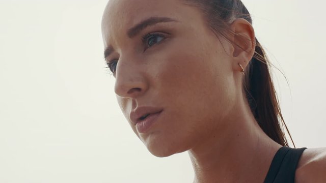 Closeup of an attractive female athlete resting after workout. Fitness woman looking focused on her workout session outdoors. 
