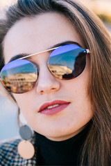 Outdoor autumn close-up portrait of young elegant fashionable woman wearing trendy sunglasses, brown coat, turtleneck, on a European city street. Copy space