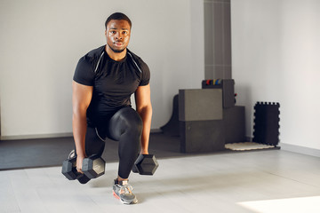 Obraz na płótnie Canvas Sports man in the gym. A black man performs exercises. Guy in a black t-shirt