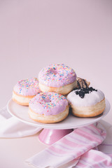 Several fresh donuts with pink glaze, on top of the pink plate, served on pink background.  