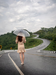 asian woman holding umbrella on extremely curved road in mountain. Nan, Thailand. sky road on hill.