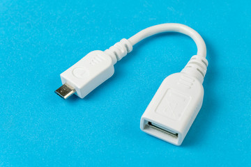 Small white USB cable on blue background, macro