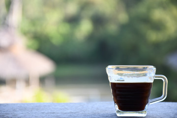 Coffee cup and Flower jar on wooden board with nature background.