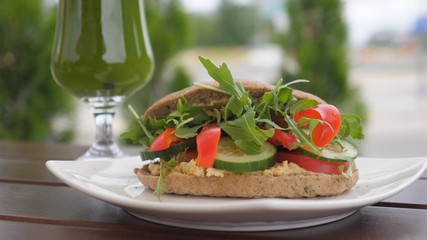 Healthy organic vegan lunch of rye sandwich filled with vegetables and green smoothie in a long glass. Healthy life style concept 