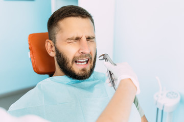 A man treats his teeth at the dentist. Dental examination at the dentist. Dental care. A man is...