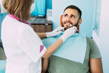 A man treats his teeth at the dentist. Dental examination at the dentist. Sound teeth. A snow-white smile. A young smiling man with beautiful teeth undergoing a dental examination. Dental care