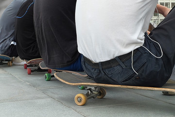 young skateboarders sit on sports equipment