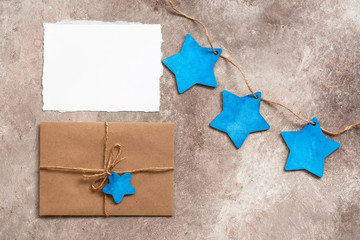 Blank card mockup, craft envelope and wooden blue stars on a beige rustic background. Letter to Santa Claus. Beautiful Christmas and New Year card. Top view, flat lay.