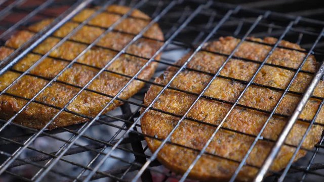 Close up of vegan meat patties in nonstick grilling basket. Making vegan burgers on barbecue. 