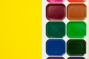 multicolored watercolor paints for painting on yellow background