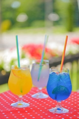 Three ice soft drinks with soda water, refreshing summer beverage. Alcohol cocktail with ice in a glass outside.