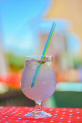 Lavander lemonade drink in a glass with plastic straw outside. Fresh natural organic herbal soft drink.