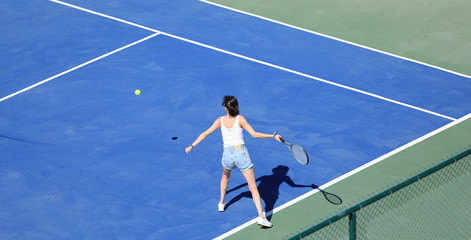 a girl hits the ball on a blue tennis court