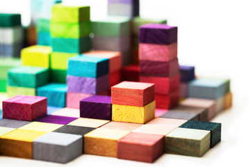 Spectrum of stacked multi-colored wooden blocks. Background or cover for something creative, diverse, expanding, rising or growing. Shallow depth of field.