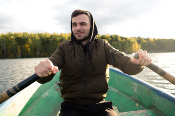 A man rowing on oars on an autumn lake