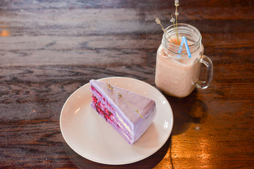 Slice of purple lavender cake with berries served with lavender flowers on a white plate.