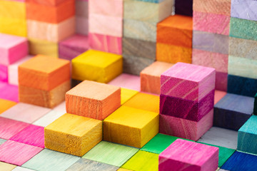 Fototapeta na wymiar Spectrum of stacked multi-colored wooden blocks. Background or cover for something creative, diverse, expanding, rising or growing. Shallow depth of field.